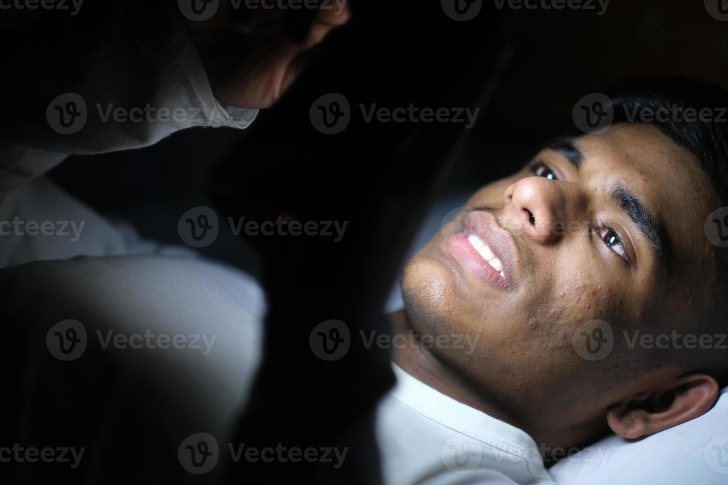 hombre usando un teléfono inteligente en la cama foto