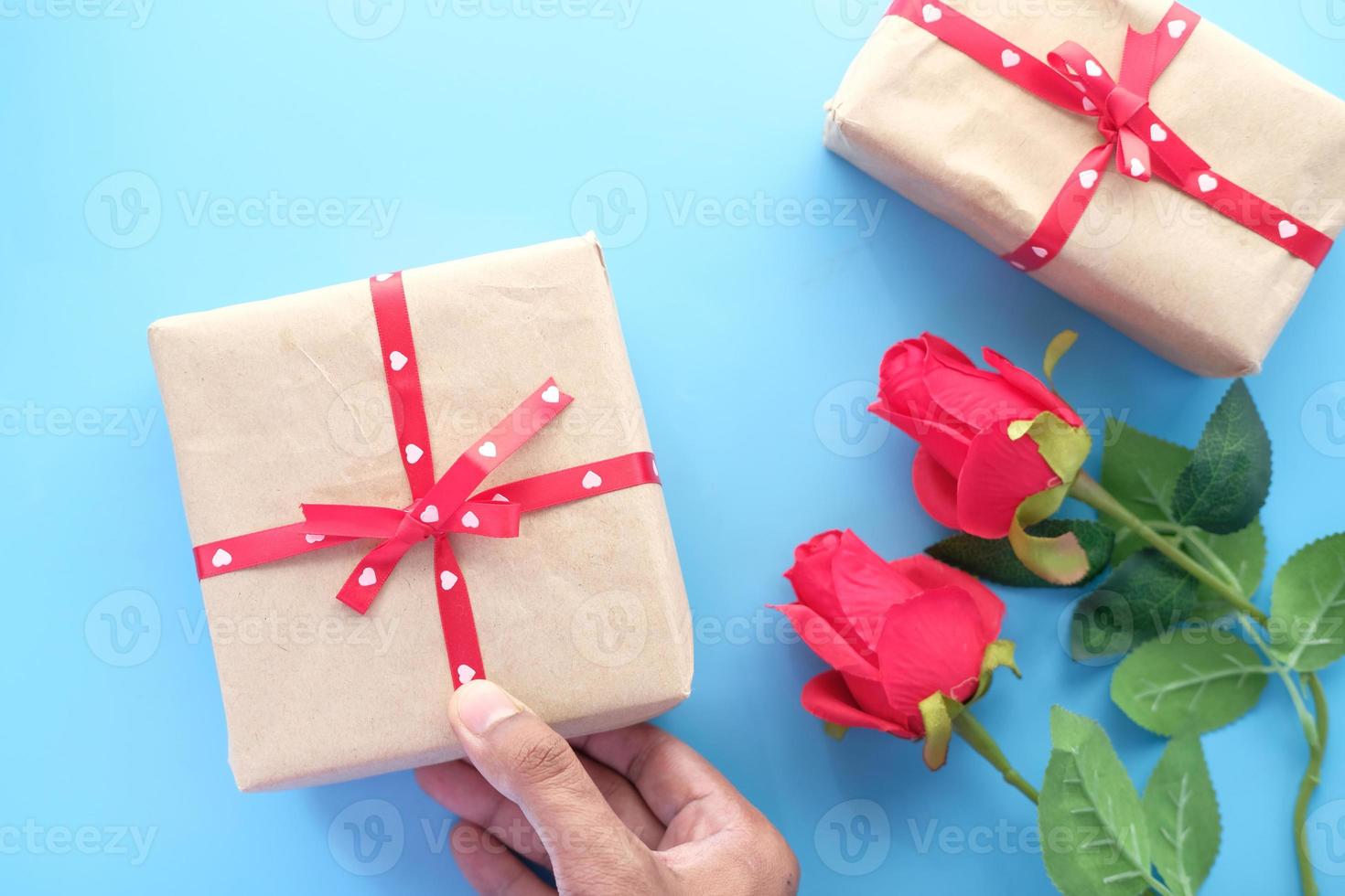 La mano del hombre sosteniendo una caja de regalo sobre fondo azul. foto