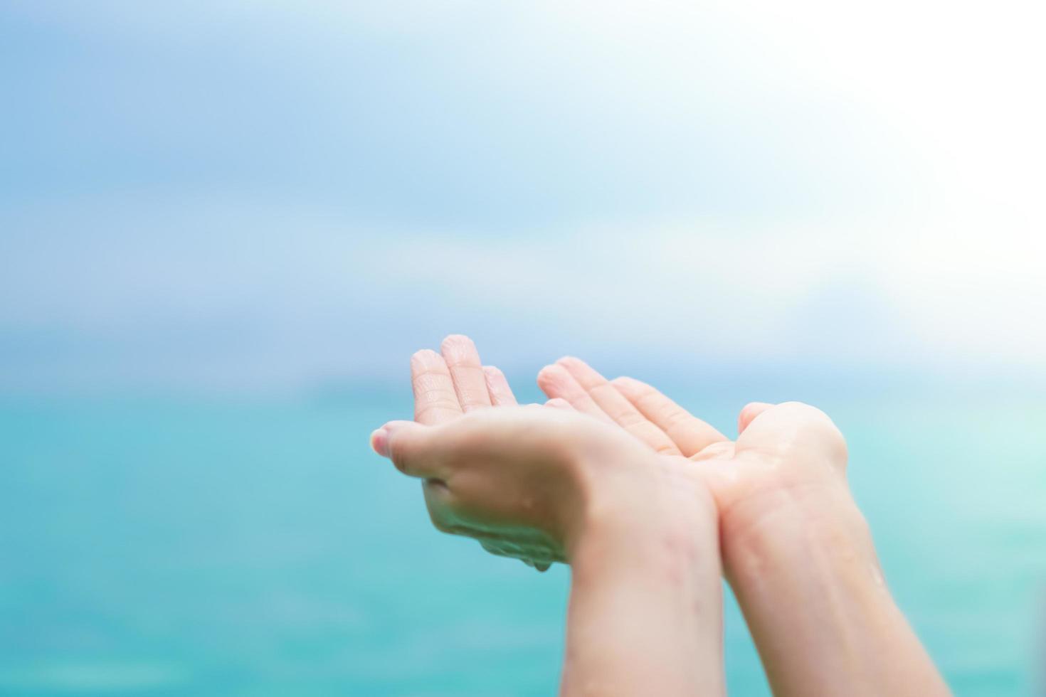 Hands placed together like praying in front of nature green background photo