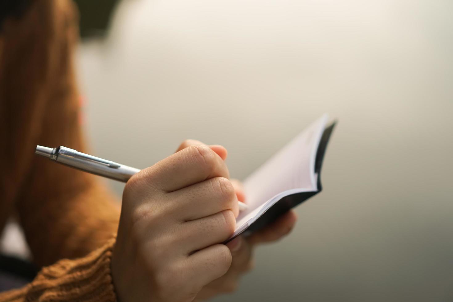 Woman hand writing in small memo notebook photo