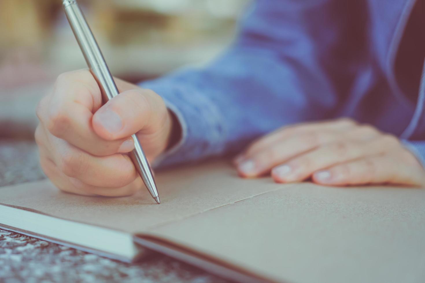 Mujer escribiendo a mano en un pequeño bloc de notas foto