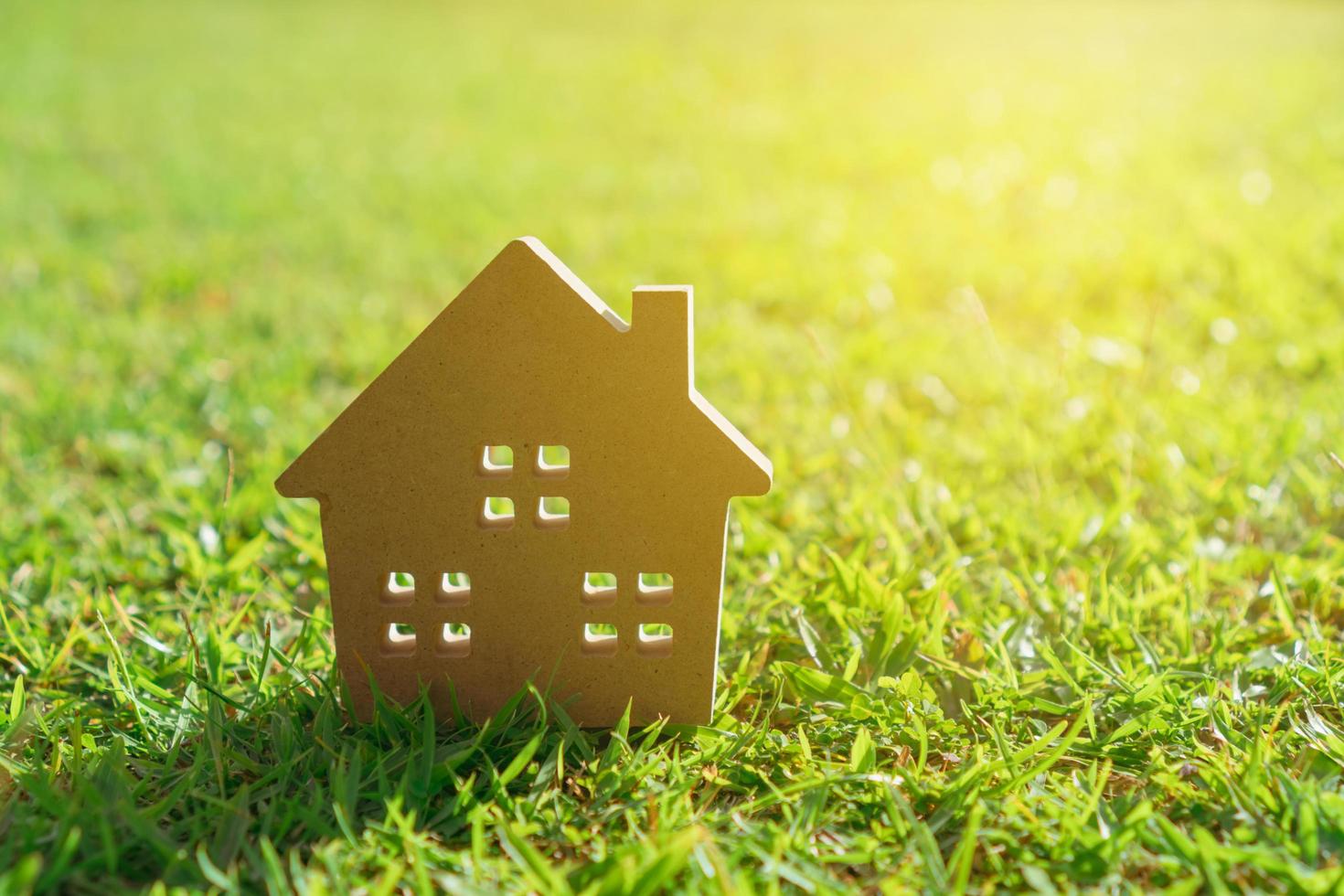 Close-up of tiny home model on grass with sunlight background photo