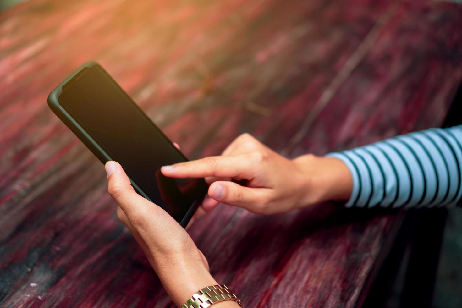 Mujer usando un teléfono inteligente en la cafetería con luz solar foto