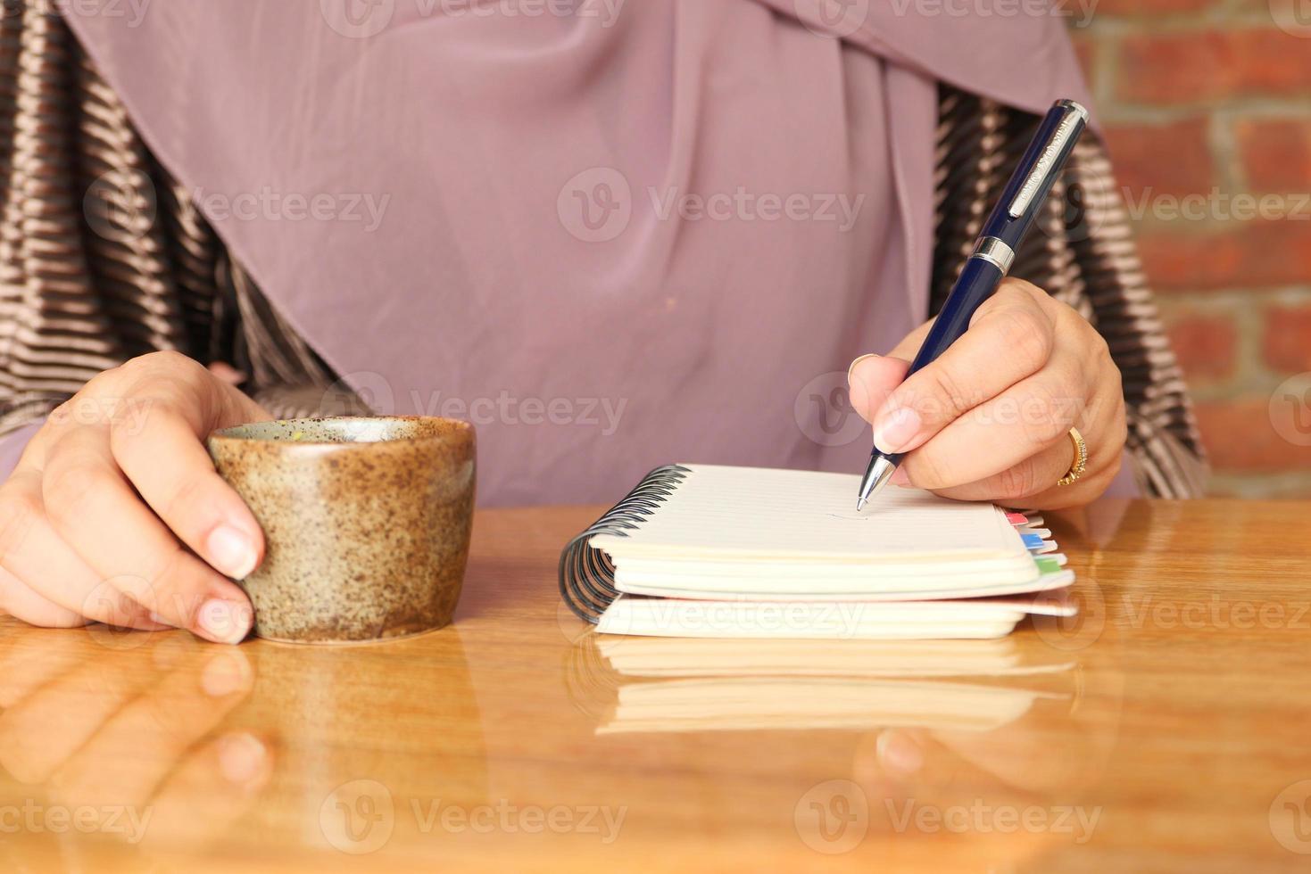 Cerca de la mano de mujer escribiendo en el bloc de notas foto