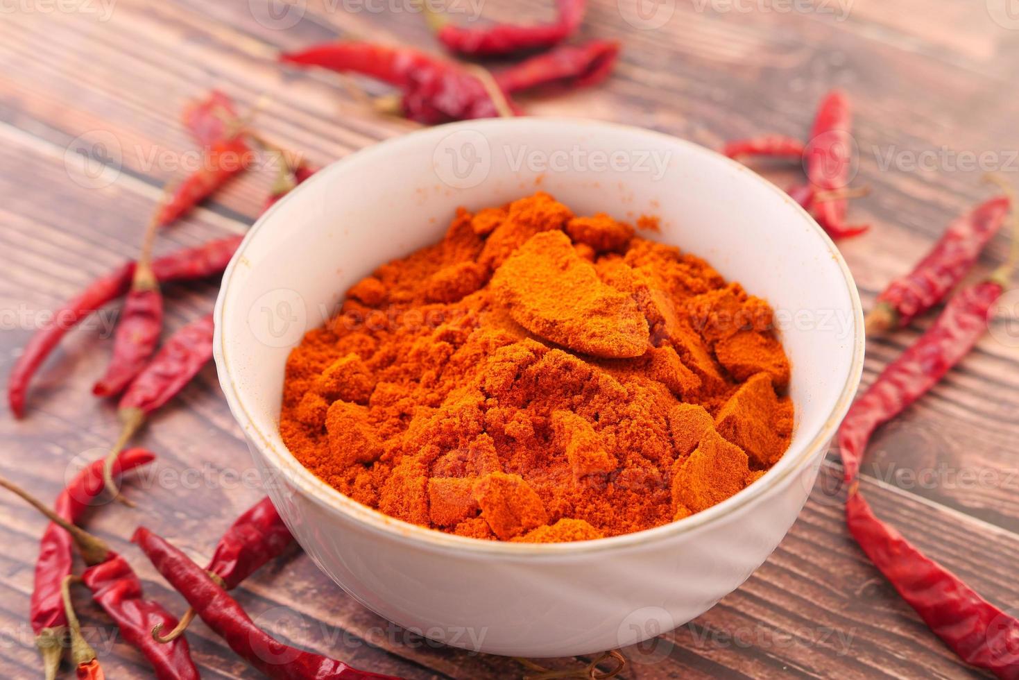 Chili powder and dried peppers on table background photo