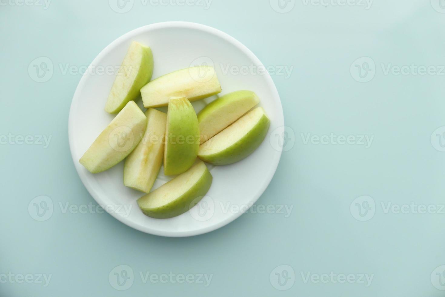 Green apple slices on blue background photo