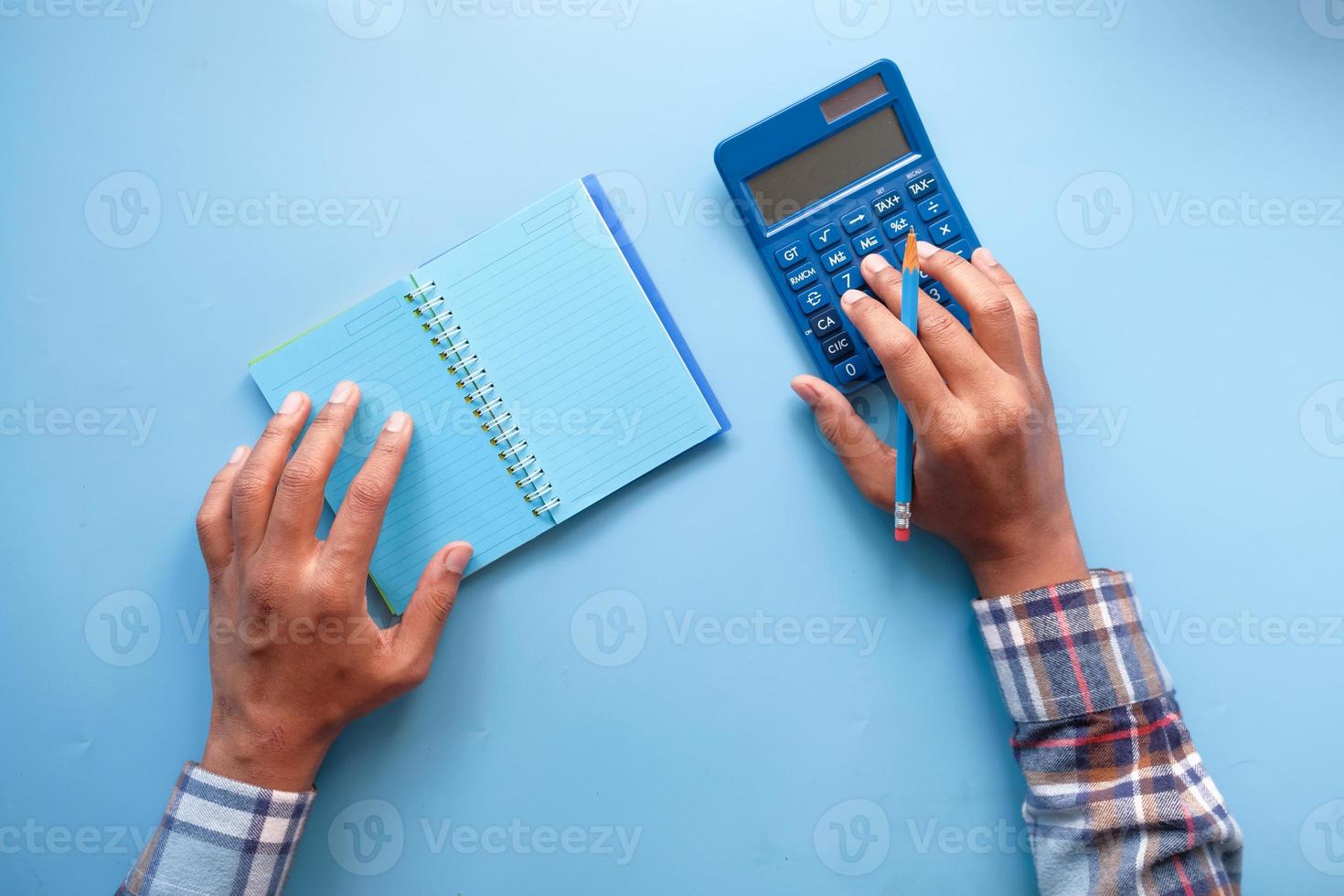 Hombre usando calculadora sobre fondo azul. foto