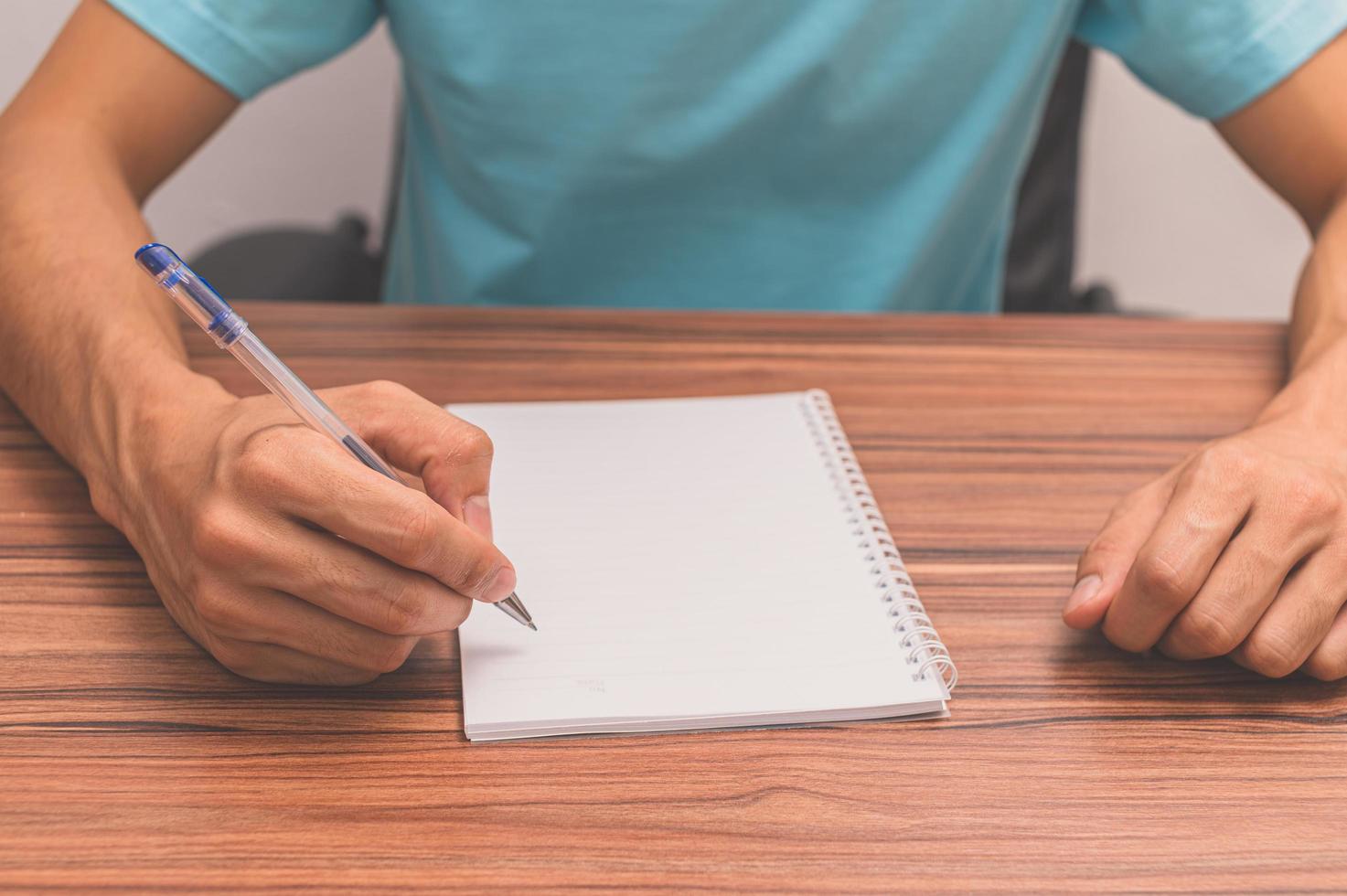 Person writing a book at a desk photo