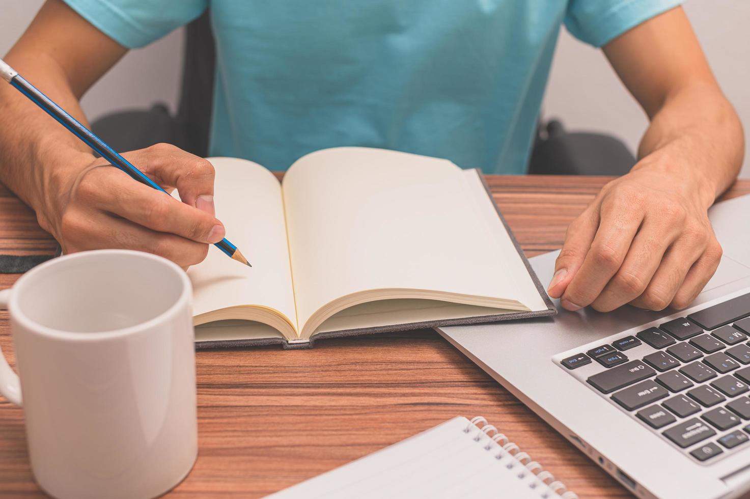 Person writing a book at a desk photo