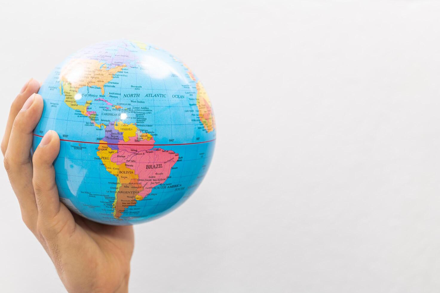 Hand holding small earth globe on white background photo