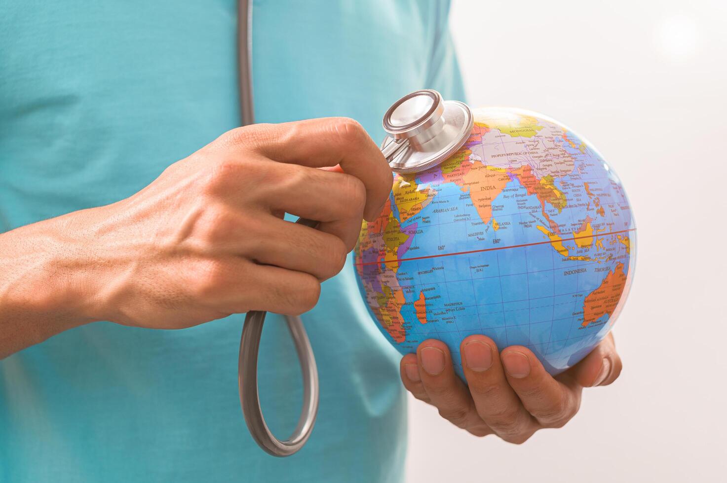 Doctor holding a stethoscope to a world globe concept photo