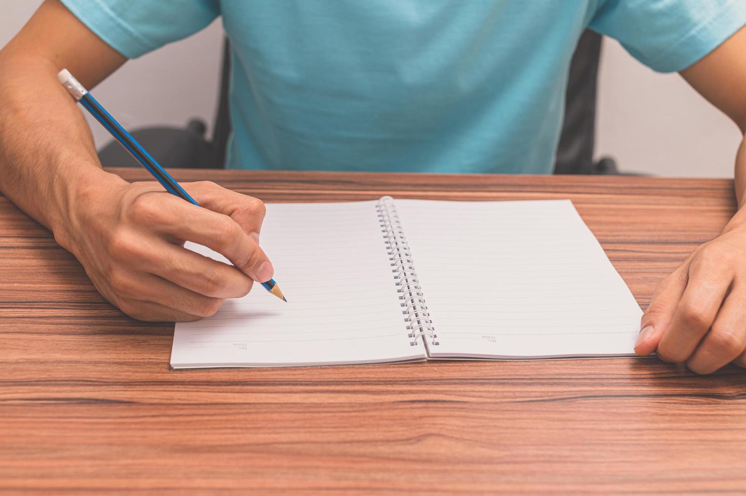 Person writing a book at a desk photo