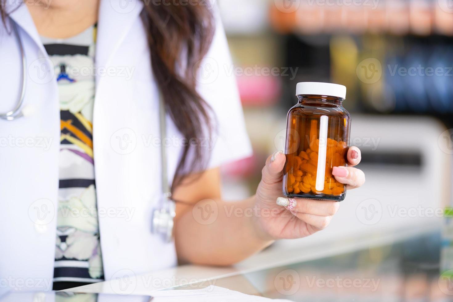 el farmacéutico sostiene un frasco de medicina en la farmacia foto