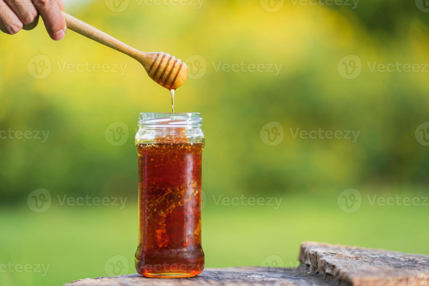 Miel que gotea del cucharón de miel sobre fondo natural foto
