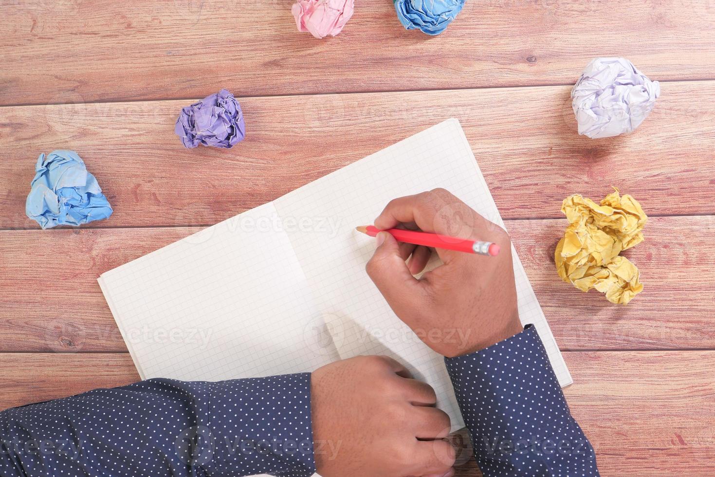 Hombre escribiendo en un diario con papel arrugado foto