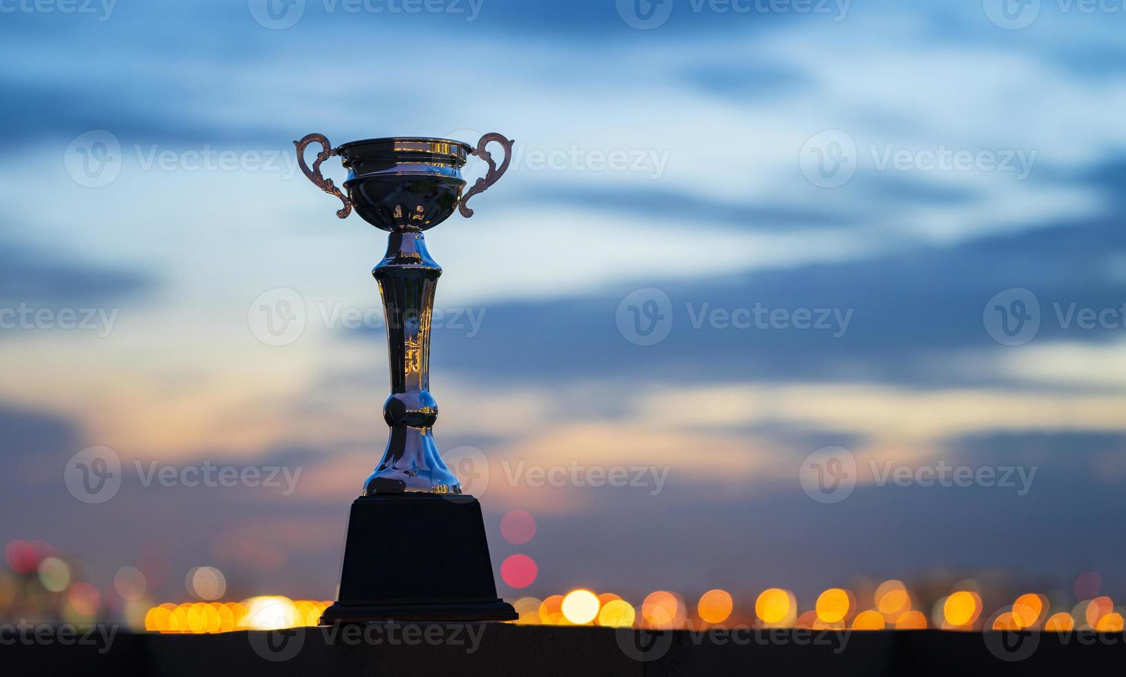 Una copa de trofeo contra el fondo del cielo crepuscular nublado foto