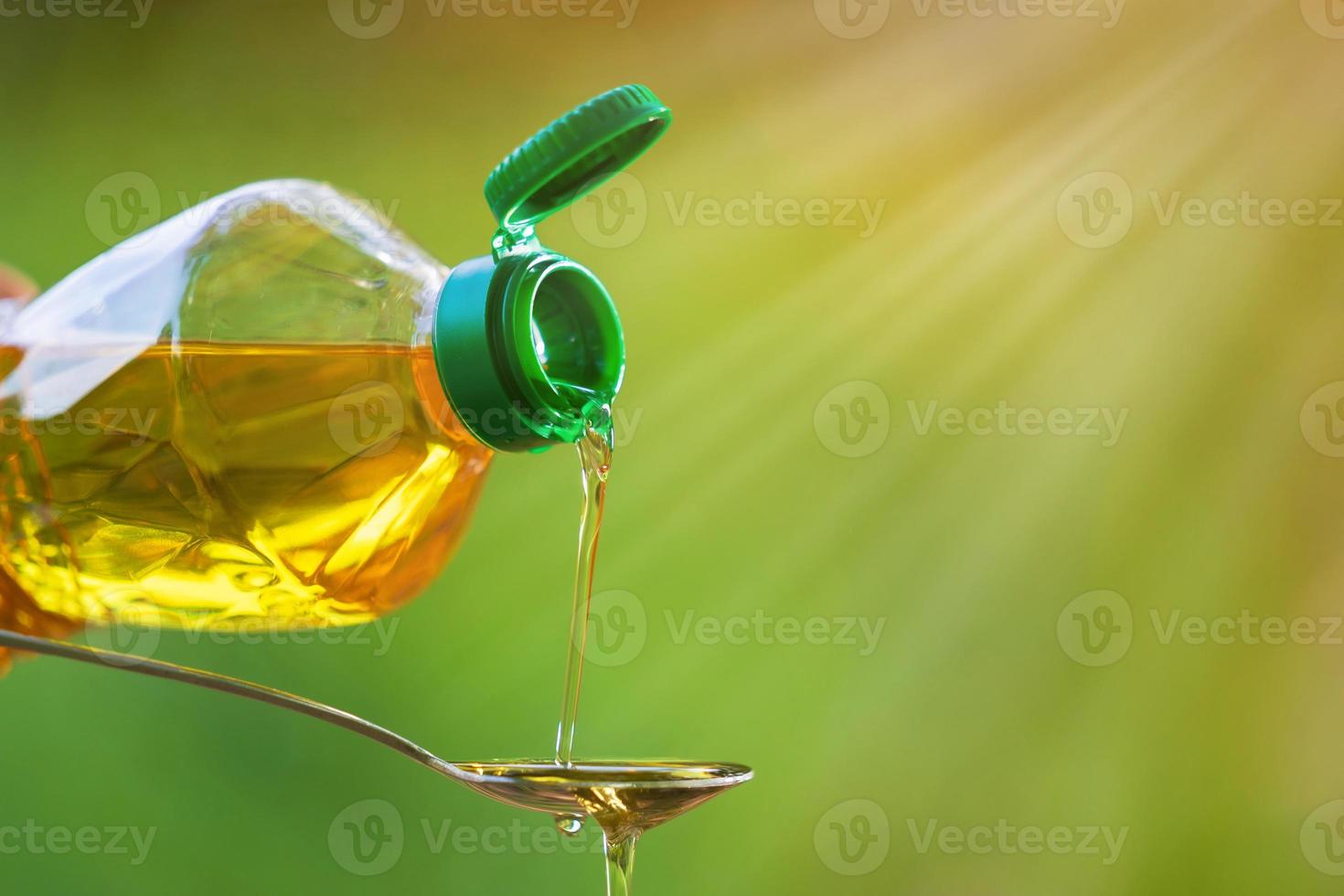 Hand pouring vegetable oil from bottle to spoon photo