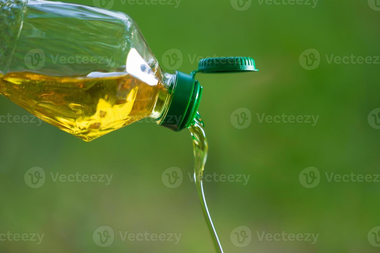 Derrame de aceite vegetal de botella con fondo de naturaleza foto