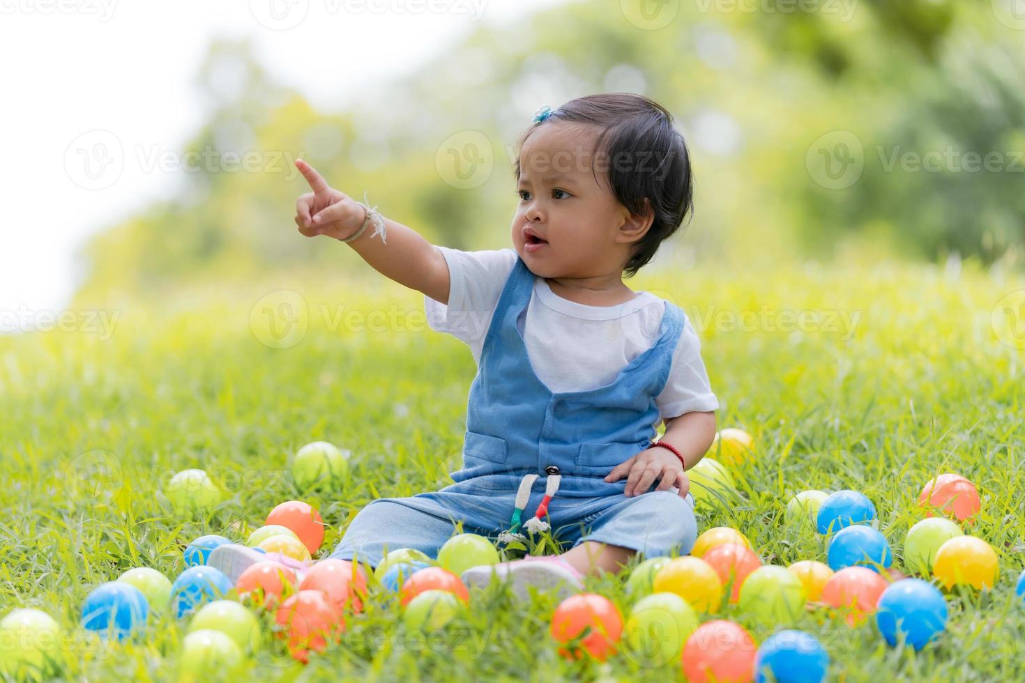 niño pequeño feliz y bolas de colores en el parque foto