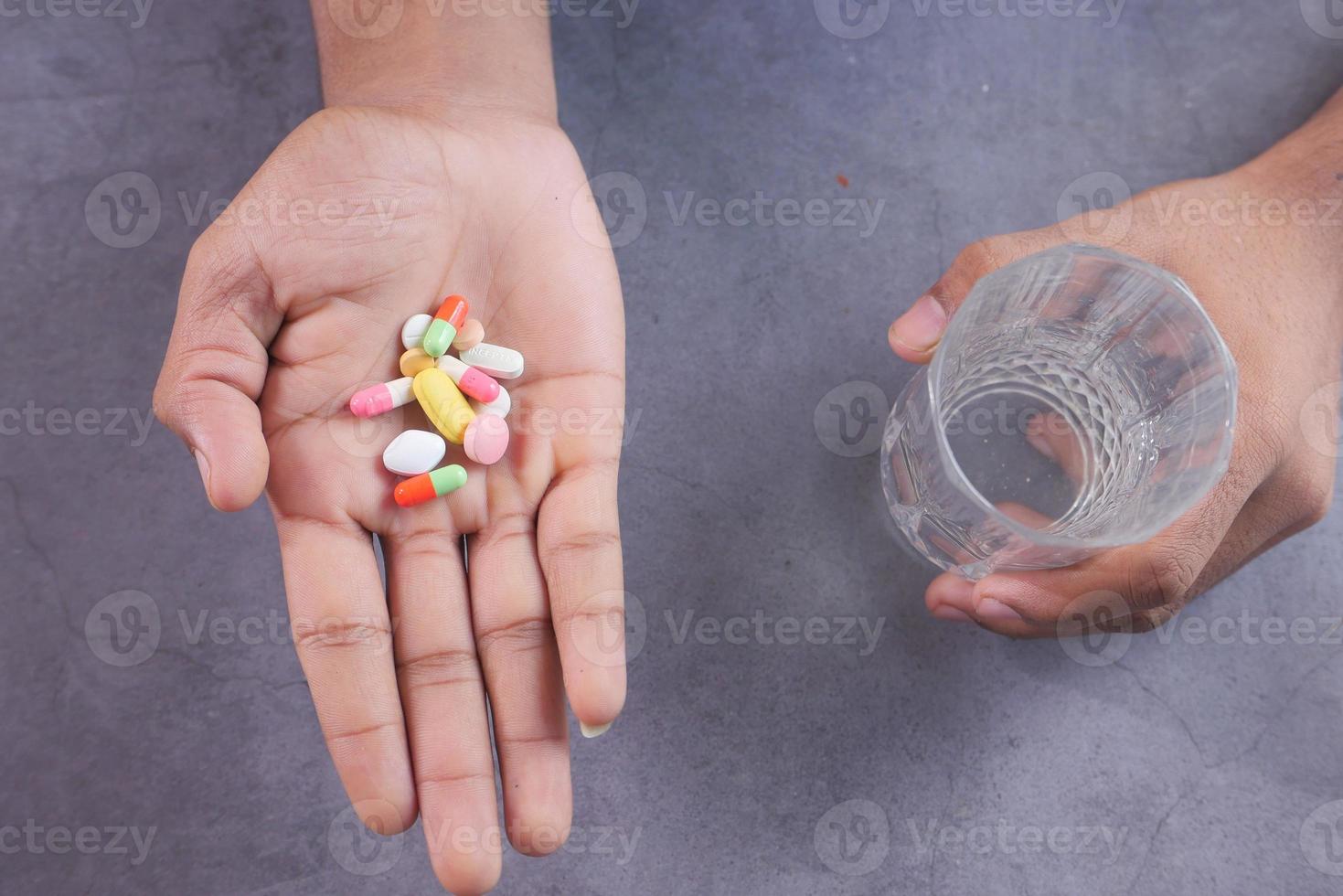 Hand holding pills and a glass of water photo