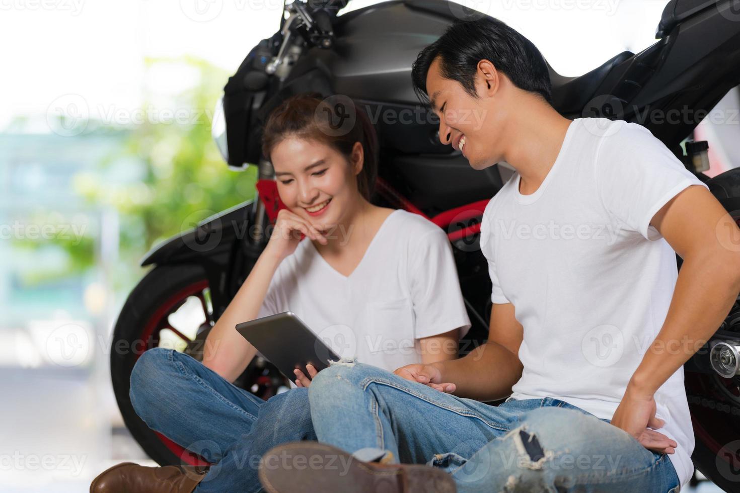 Pareja feliz usando tableta digital en casa con un fondo de motocicleta foto