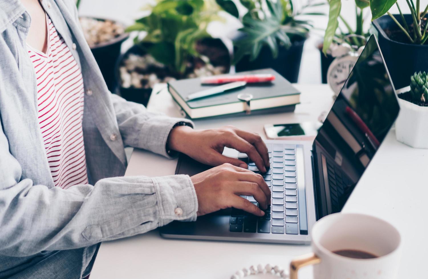 Woman working on clean nature workspace at home with laptop photo