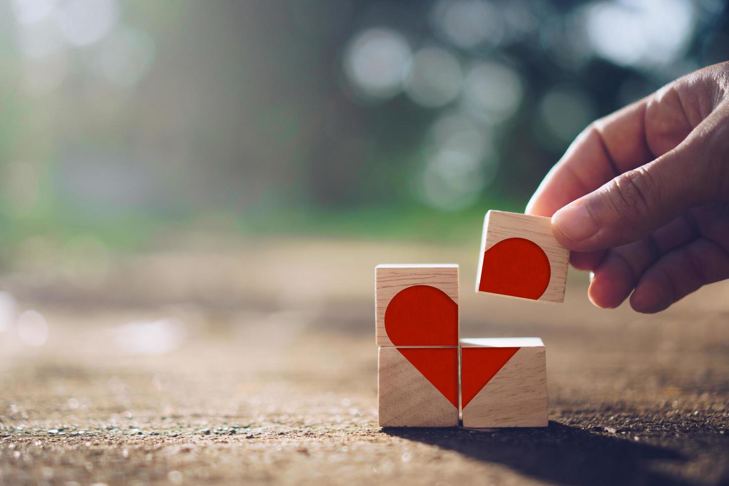 Hand holding a wooden cube with heart sign icon with nature sunlight photo