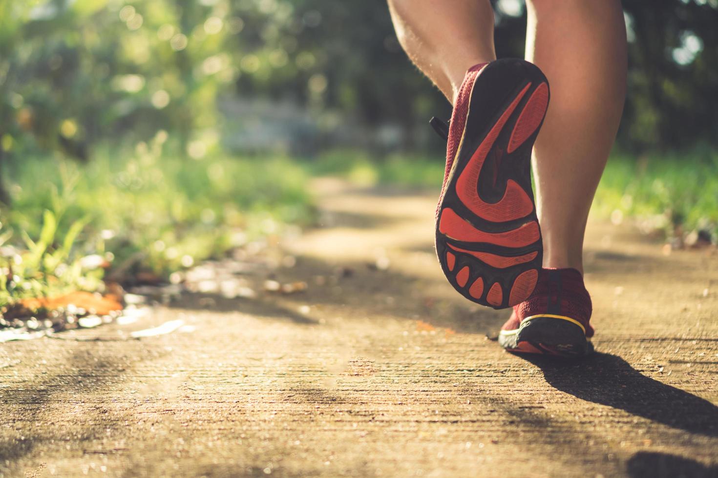 Mujer vistiendo zapatos para correr y corriendo sobre fondo verde de la naturaleza foto
