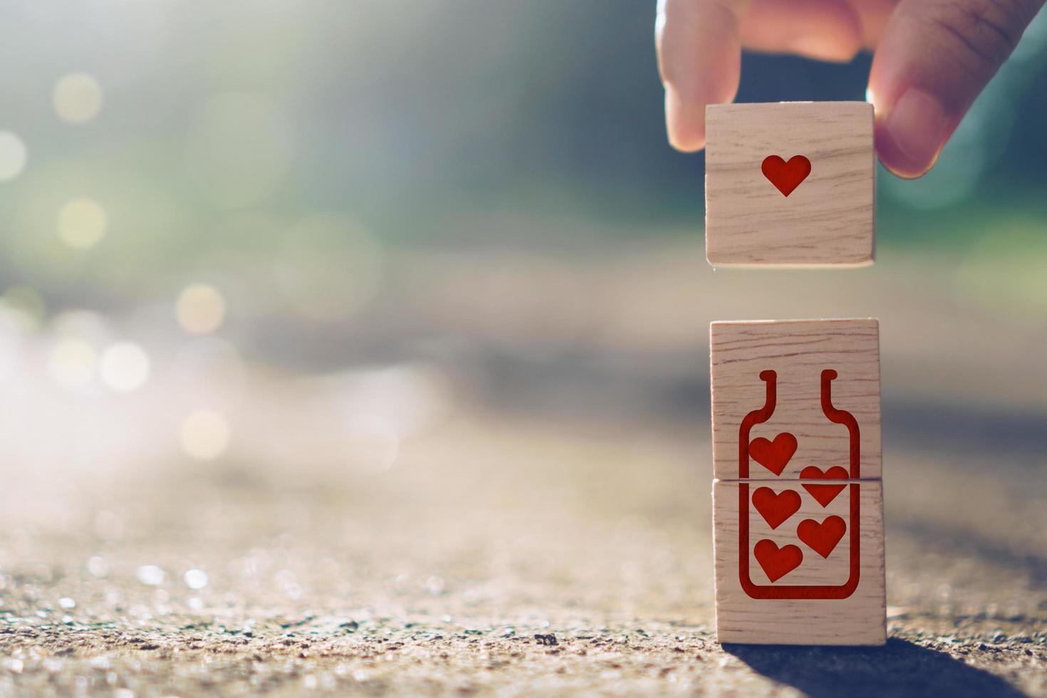 Mano sosteniendo un cubo de madera con icono de signo de corazón con luz solar natural foto