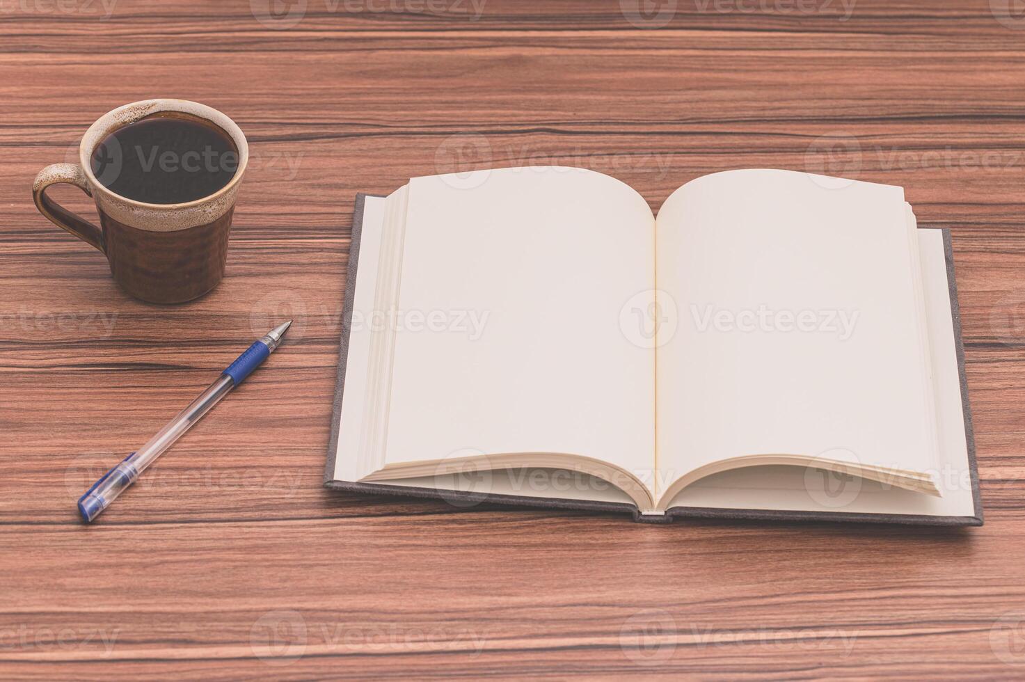 Open book, pen and coffee on wooden table photo