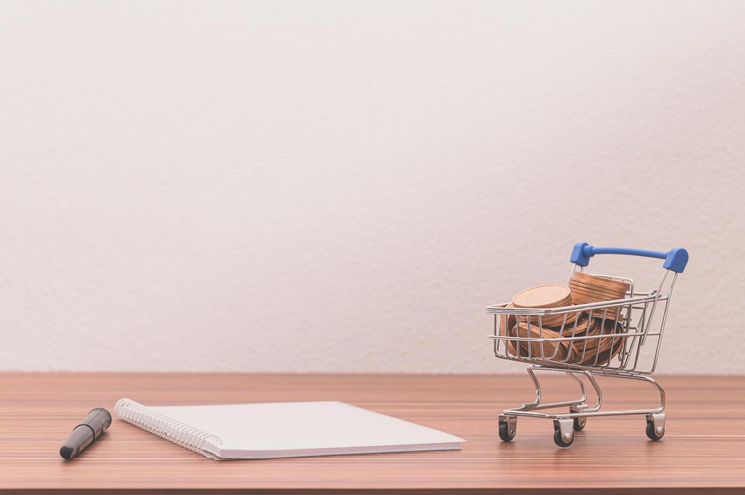 Notebook and coins in a small shopping cart on the desk photo