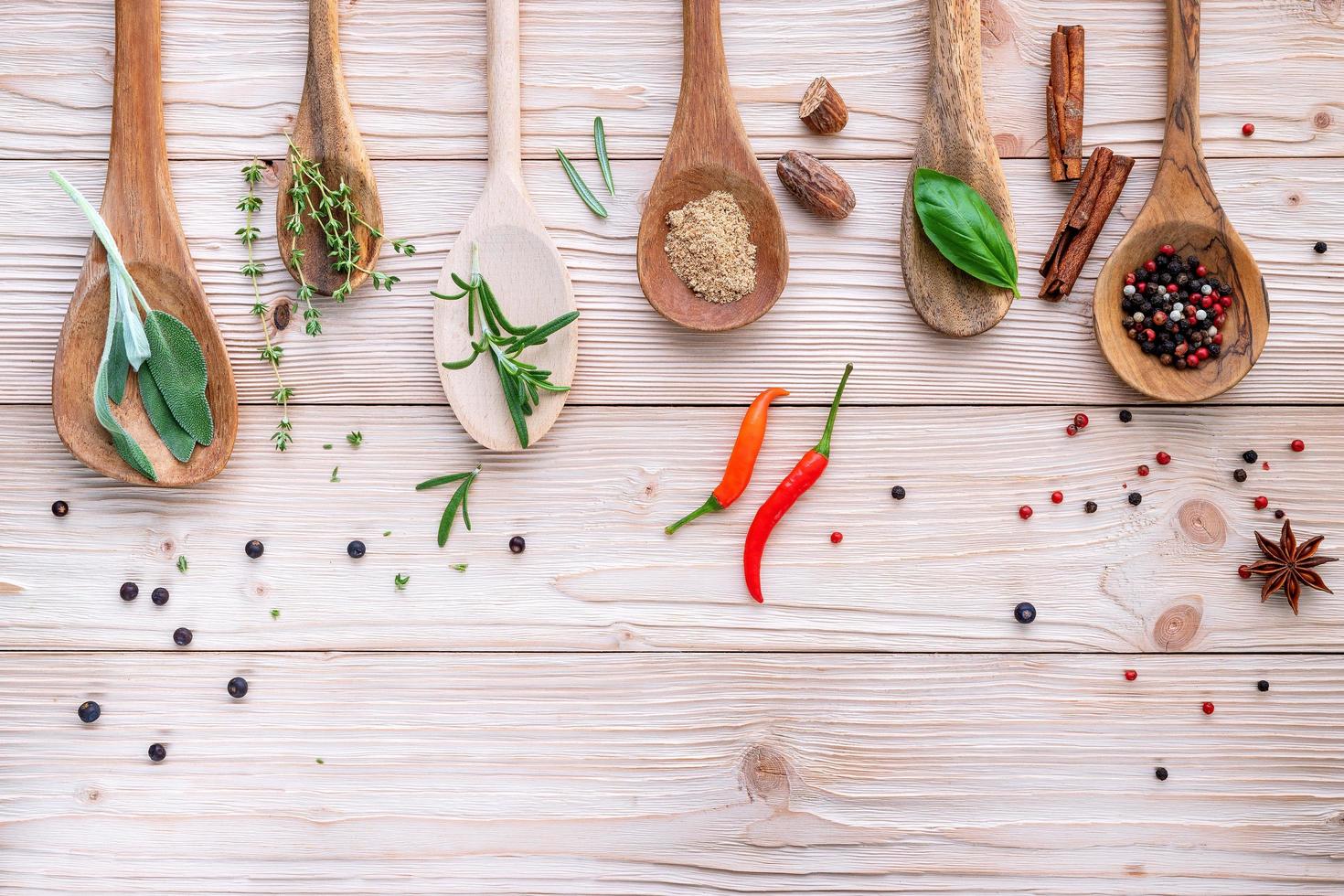 Spices and herbs in wooden spoons on a wooden background photo