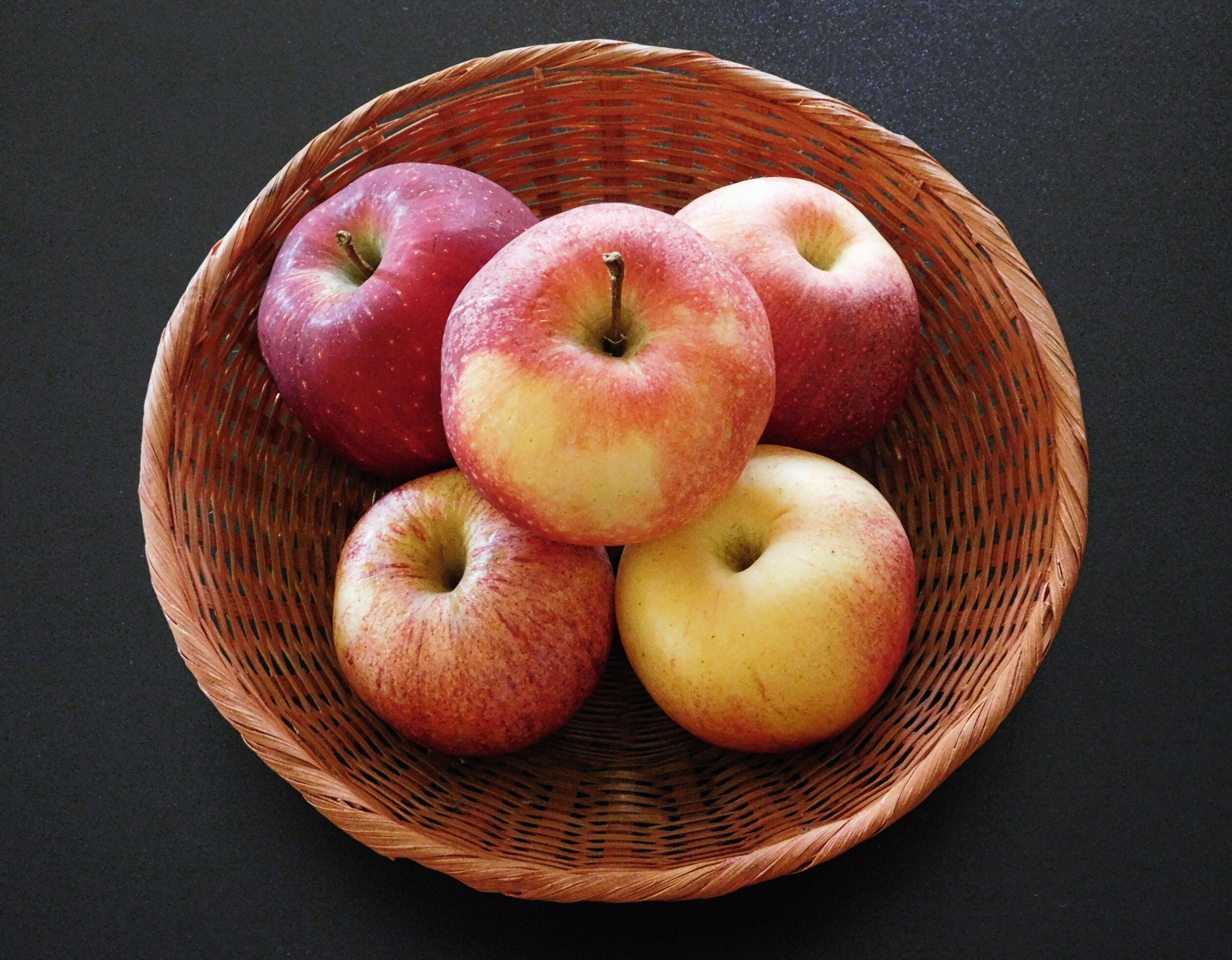 Five apples in a wicker basket on a dark table background 2077037 Stock