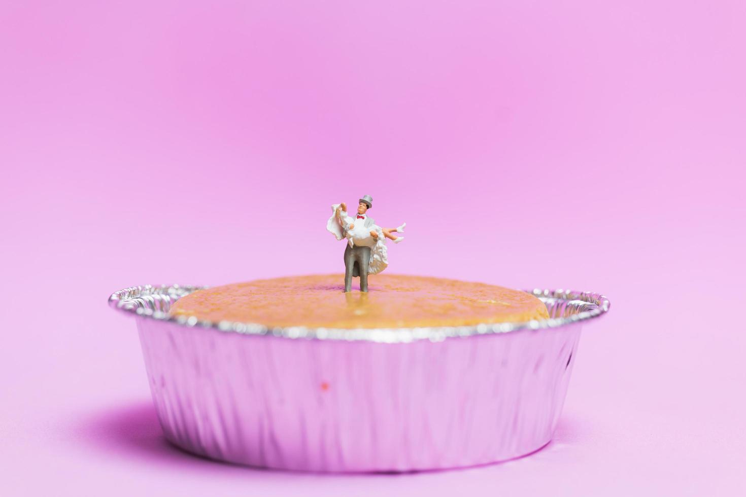 Boda en miniatura de una pareja de novios sobre un fondo rosa, concepto de día de San Valentín foto