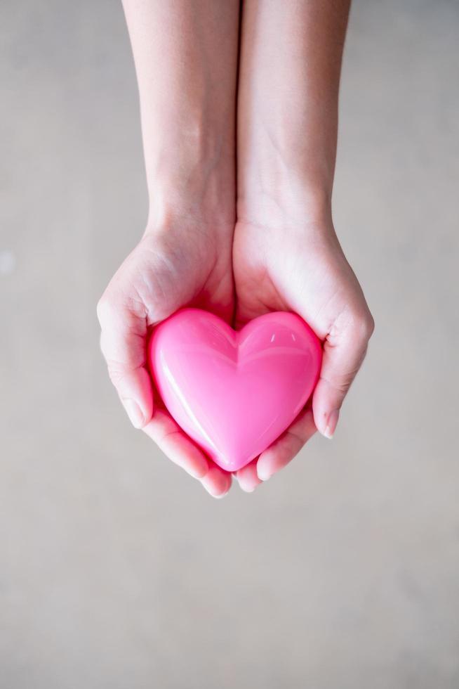 mano femenina sosteniendo un corazón rosa, un concepto de salud, medicina y caridad foto