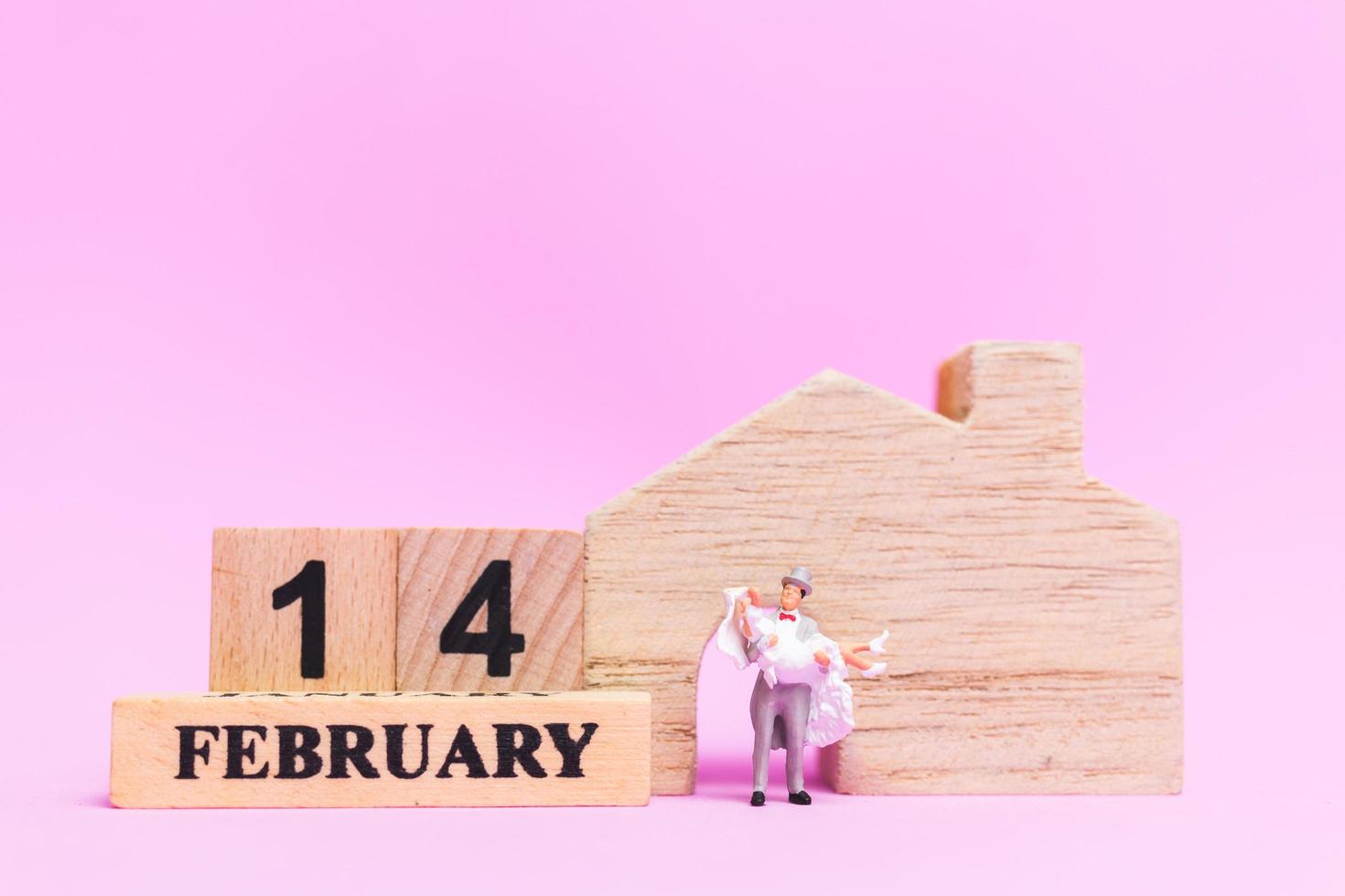 Miniature wedding of a bride and groom couple on a pink background, Valentine's Day concept photo