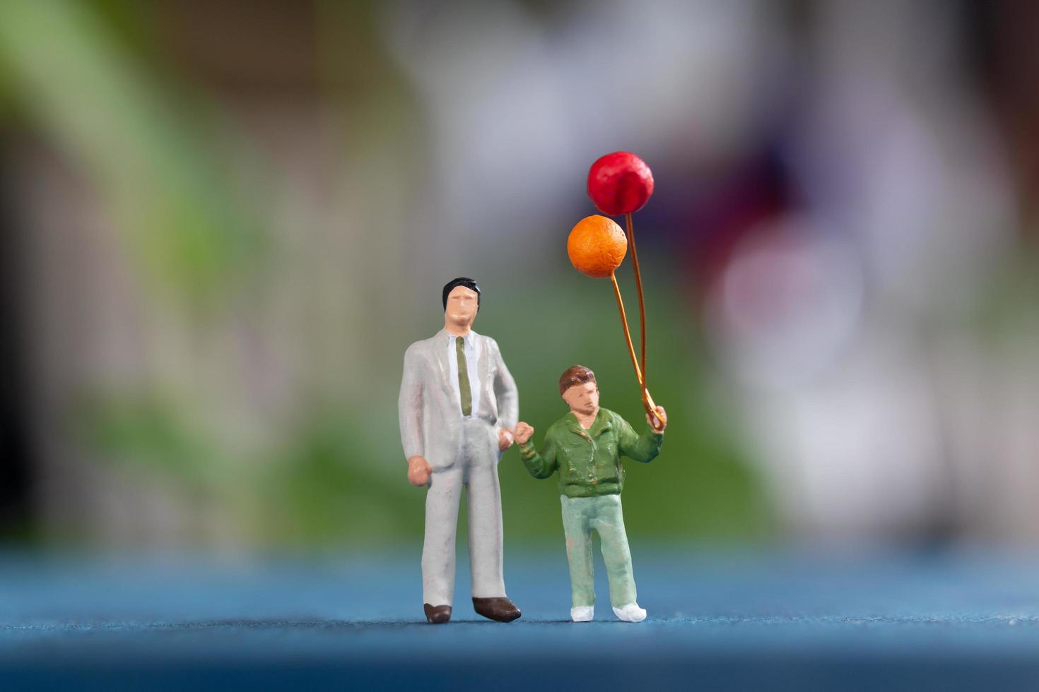 Miniature happy family holding balloons on a blurry background photo