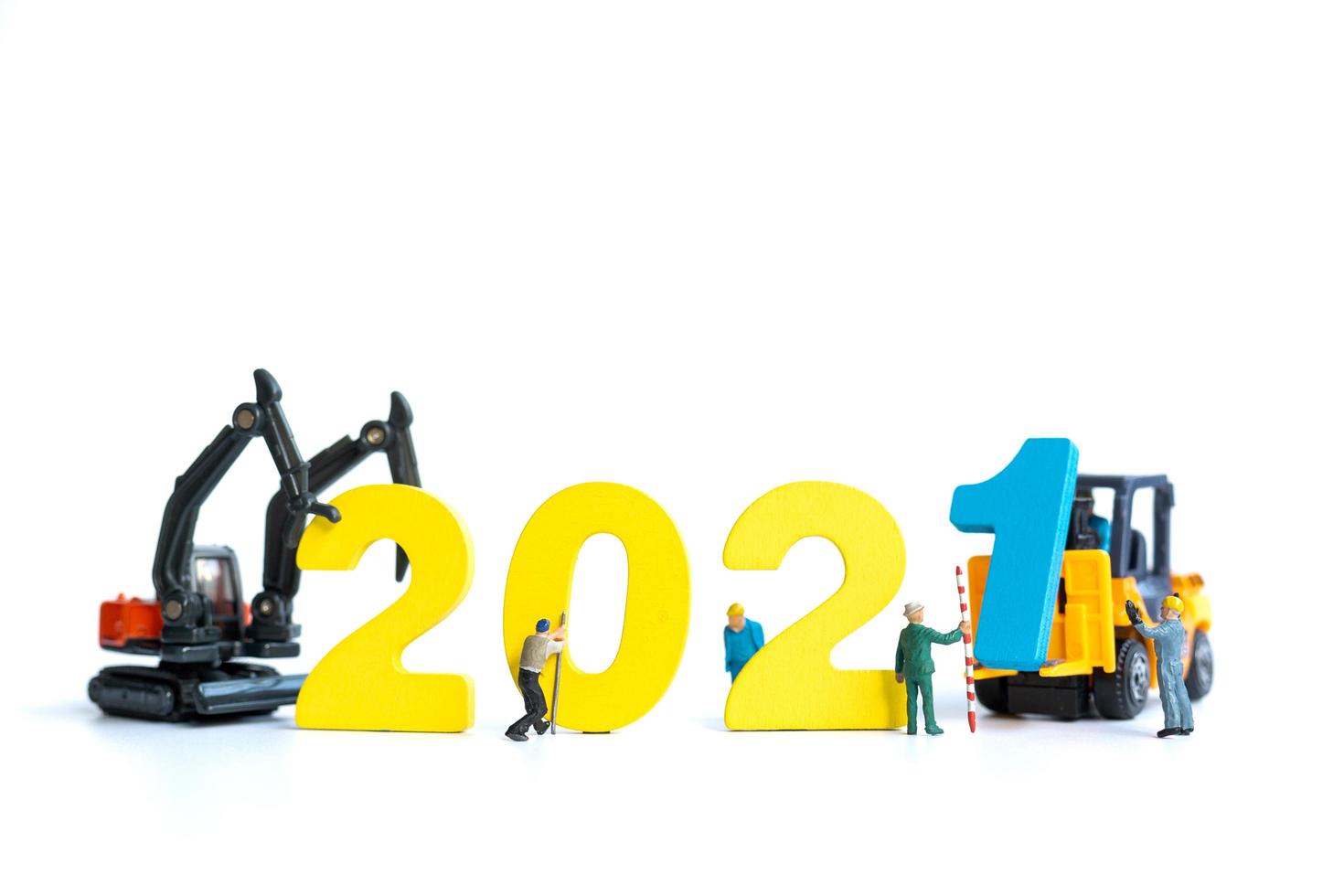 Miniature workers building wooden numbers 2021, Happy New Year concept photo