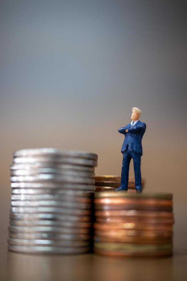 Miniature small businessmen standing with a stack of coins, business growth concept photo