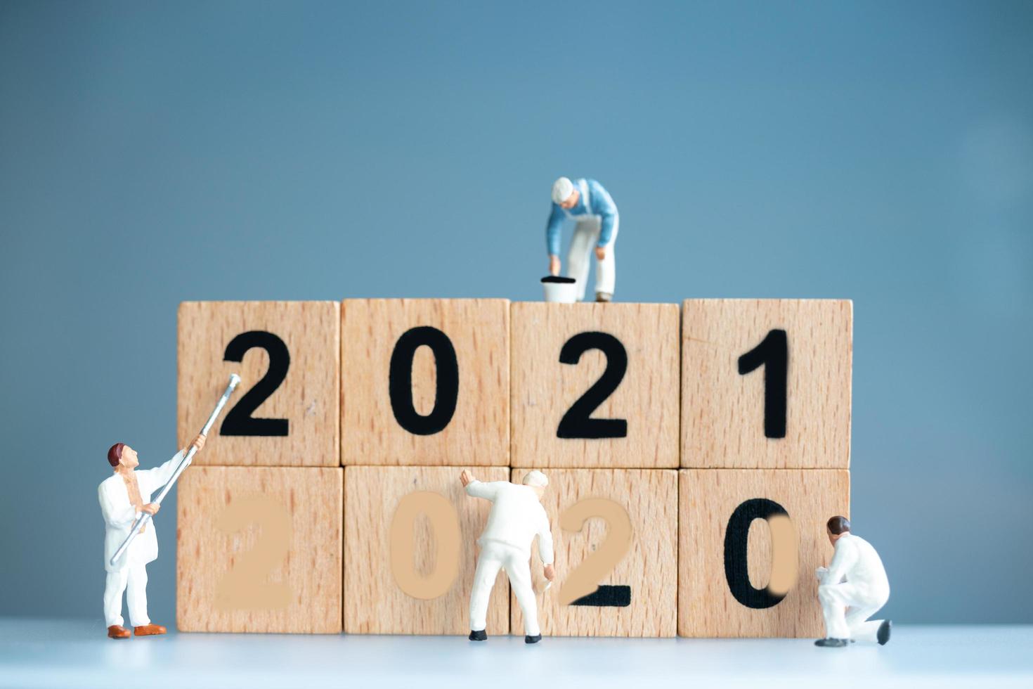 Trabajadores en miniatura pintando 2021 y eliminando números de 2020, concepto de feliz año nuevo foto