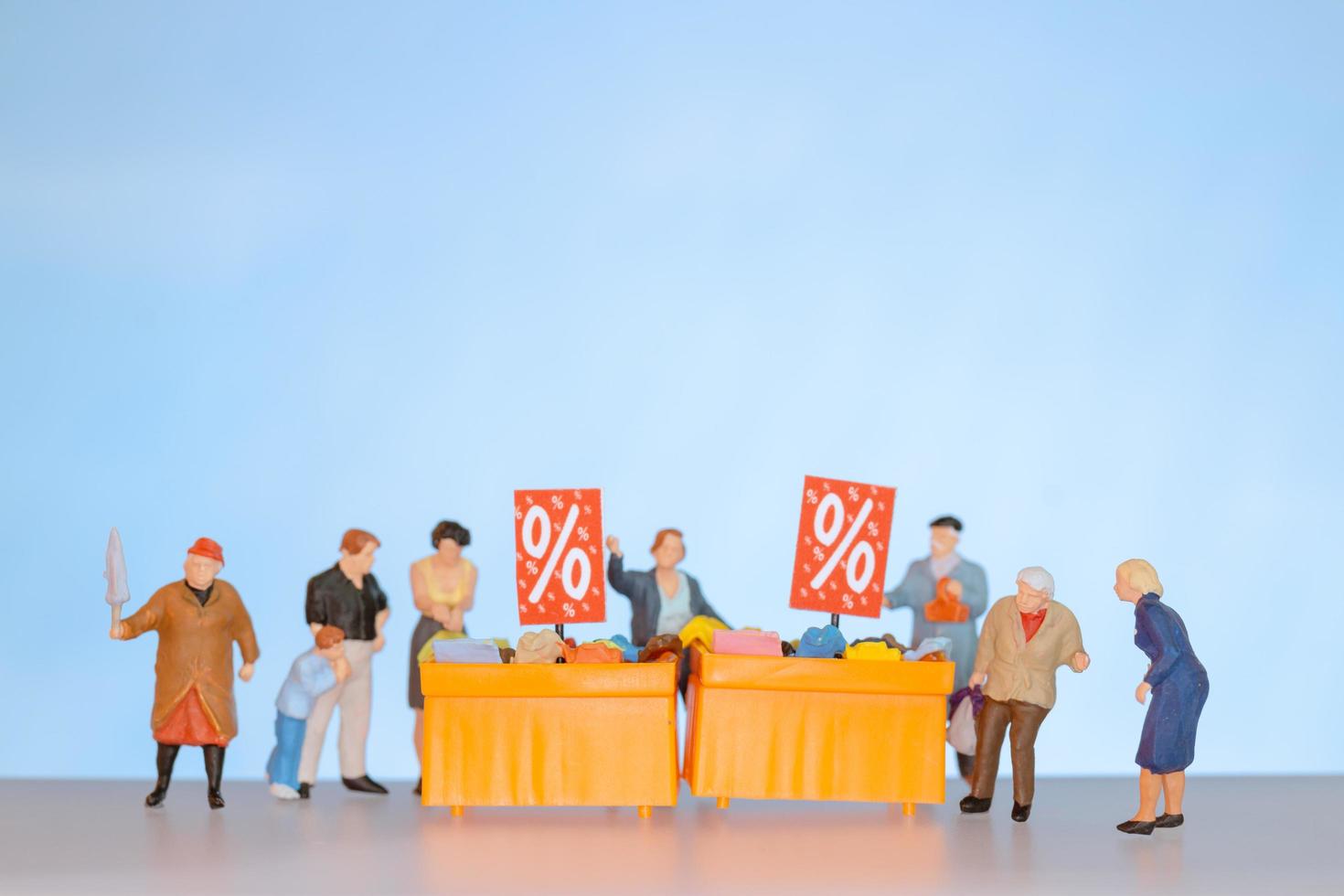 Miniature people shopping discounted items on a table photo