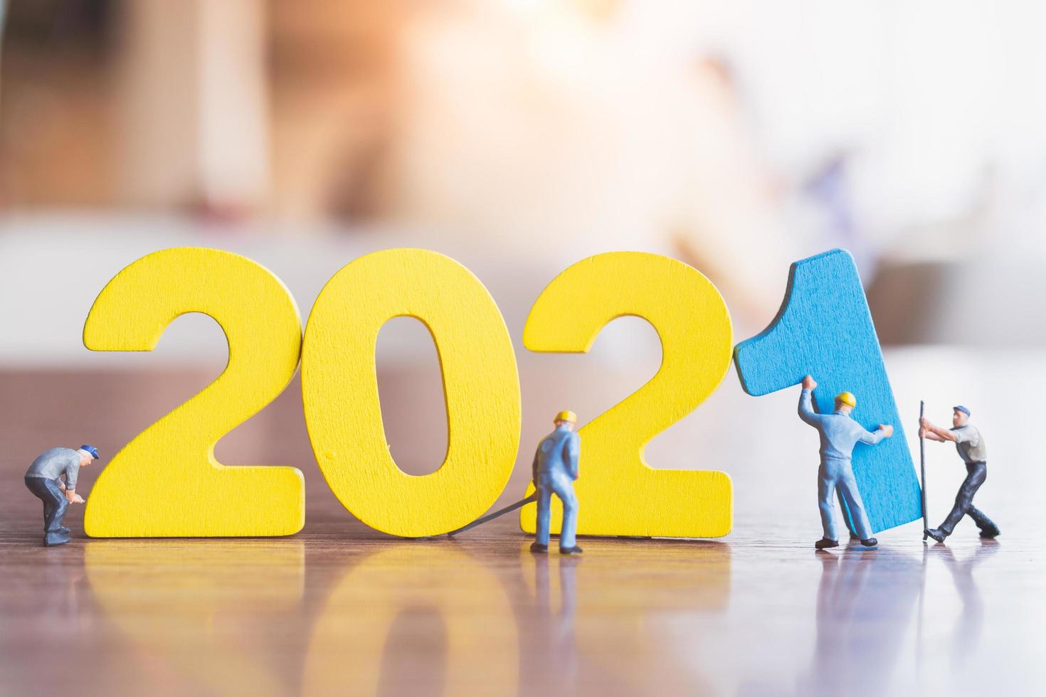 Miniature workers building wooden numbers 2021, Happy New Year concept photo