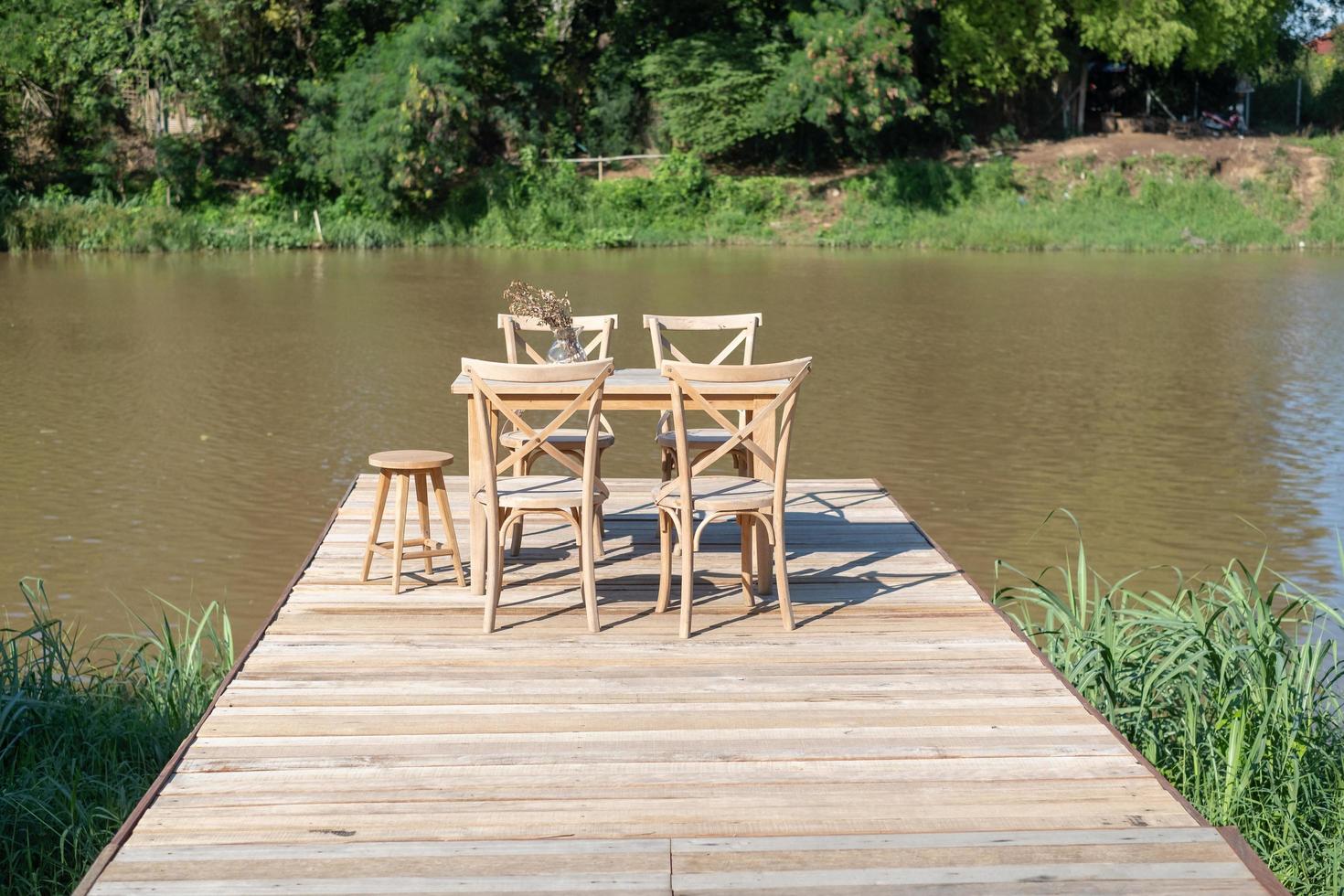 Desk and chair on a long wooden bridge near the river photo