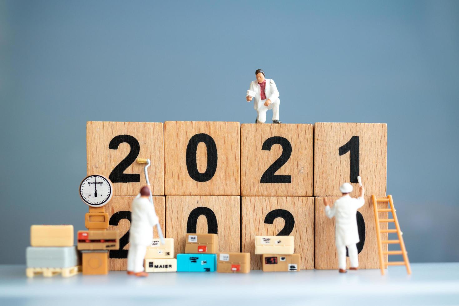 Trabajadores en miniatura pintando 2021 y eliminando números de 2020, concepto de feliz año nuevo foto