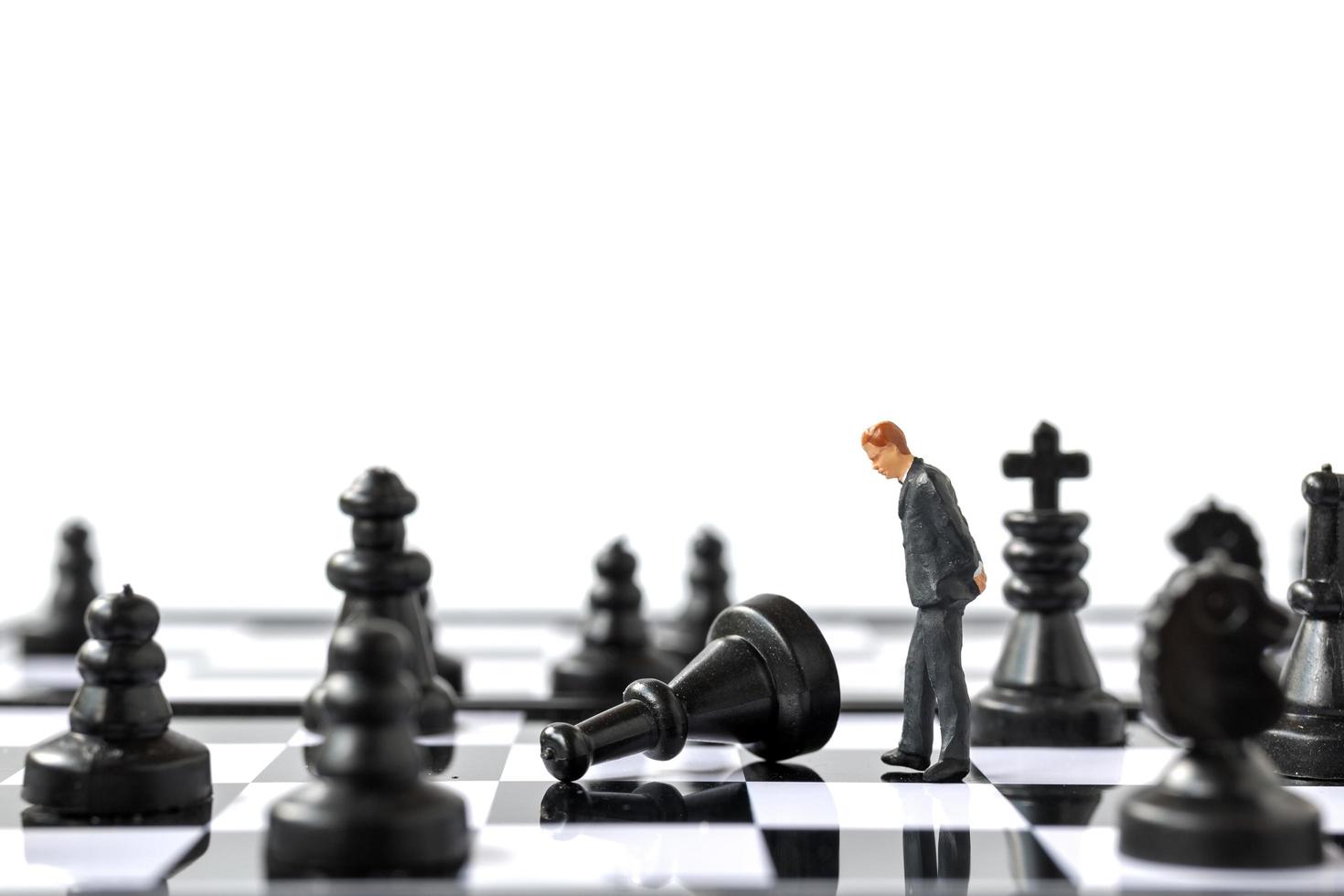 Miniature businessman standing on a chessboard, business and competition concept photo