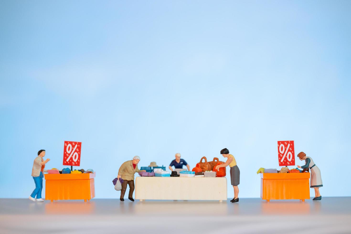 Miniature people shopping discounted items on a table photo