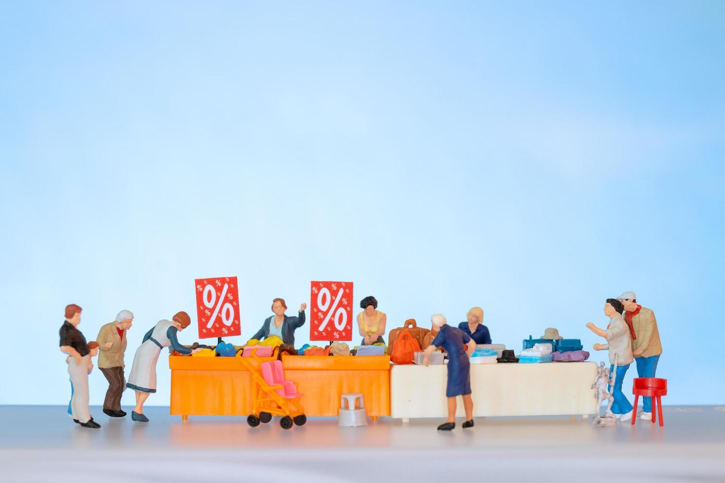 Miniature people shopping discounted items on a table photo