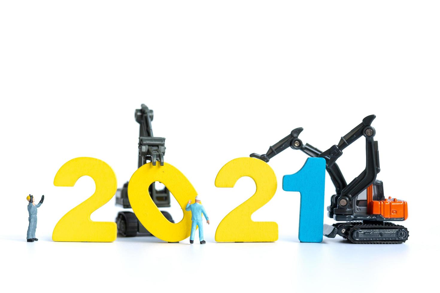 Miniature workers building wooden numbers 2021, Happy New Year concept photo