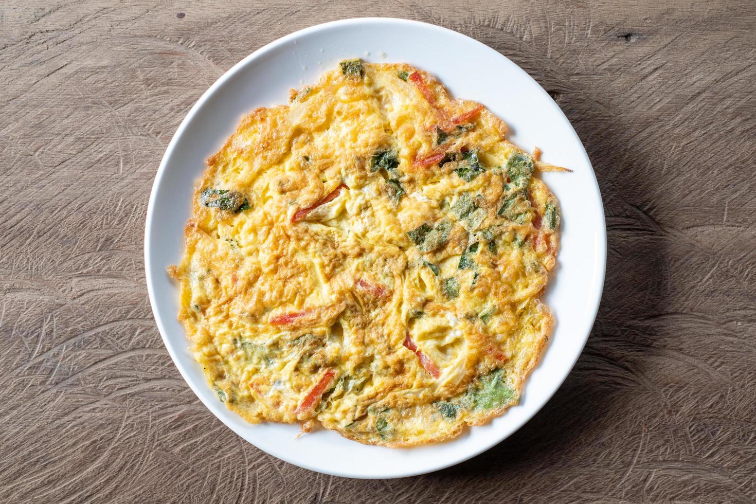 Top view of an omelet with green tea leaves served on a wood table photo