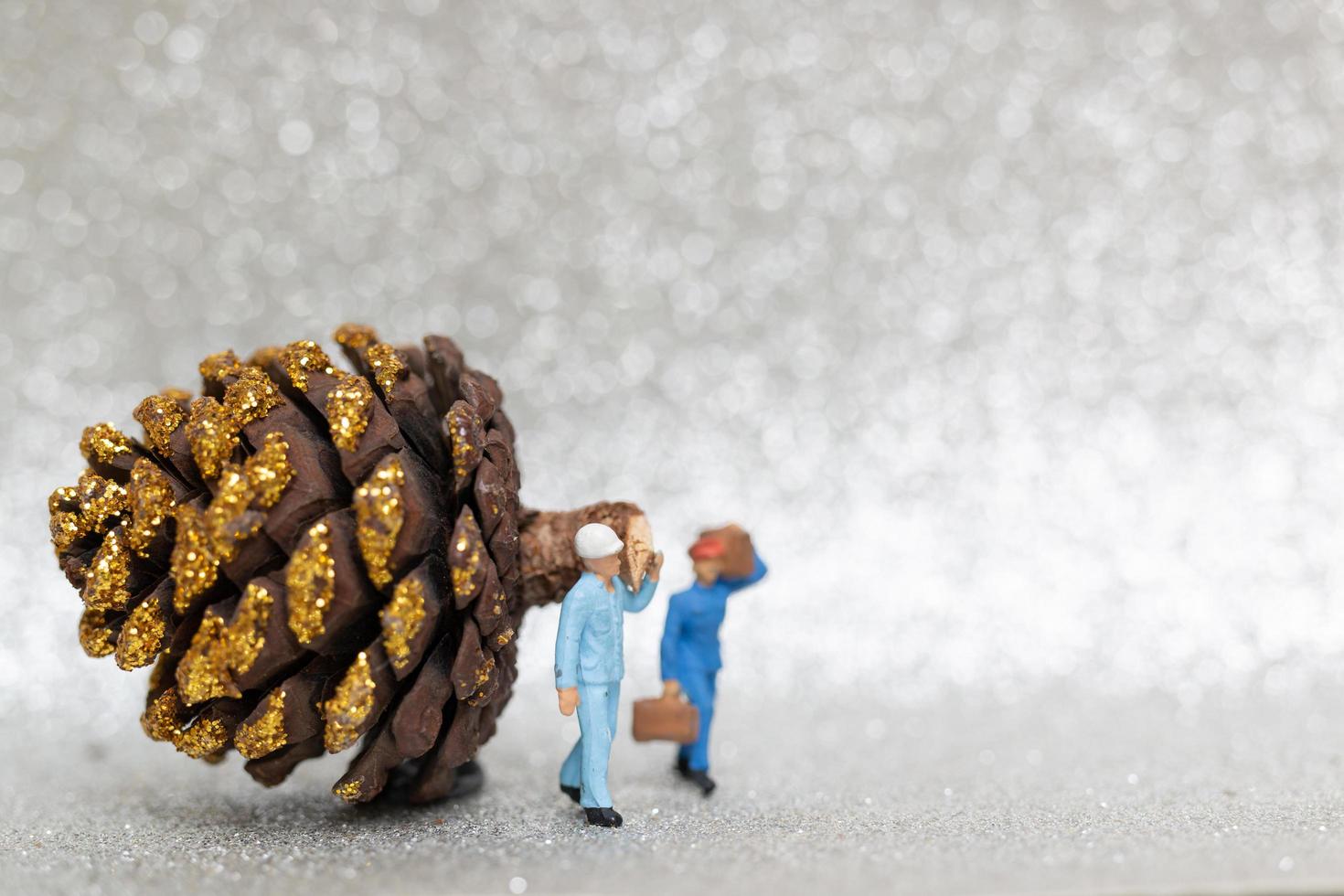 Miniature workers preparing a Christmas pine cone, Christmas and Happy New Year concept photo